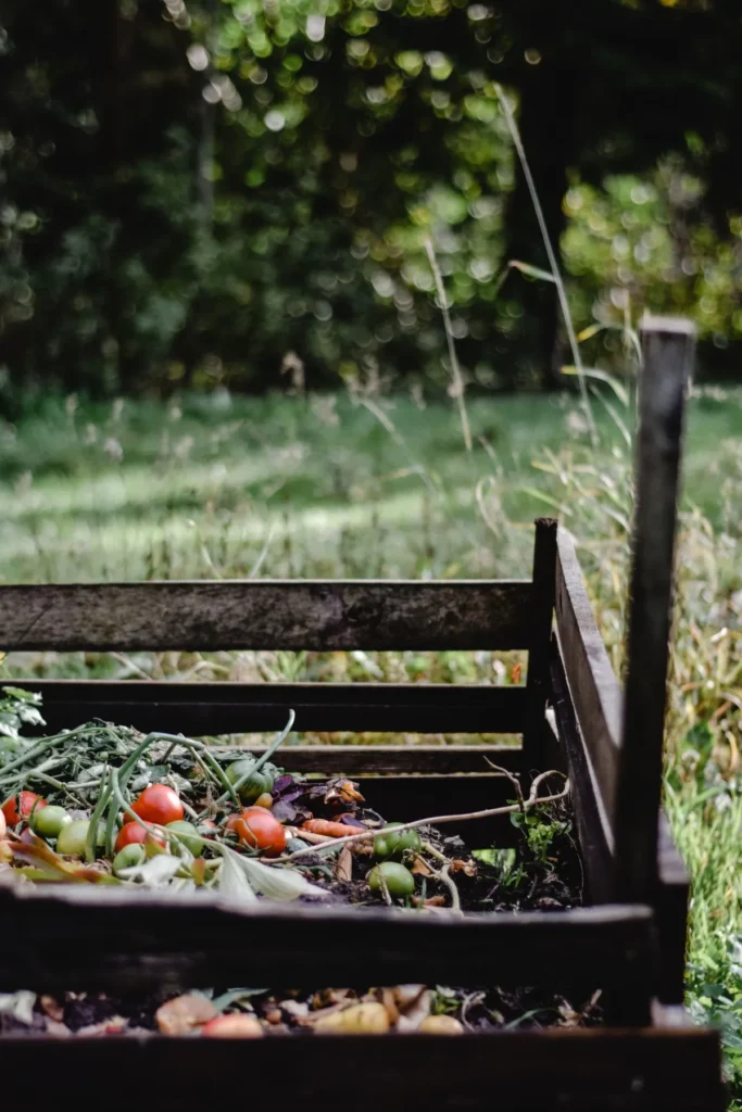 Bac à compost en bois rempli d'épluchures et de légumes au fond d'un jardin